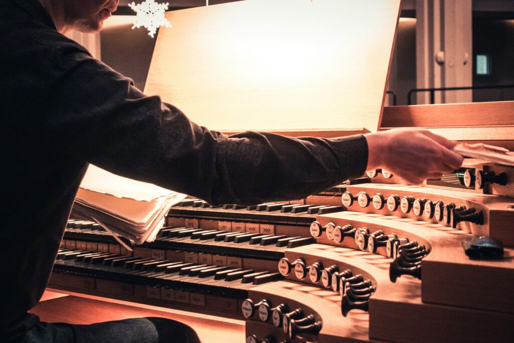Organist preparing sheet music at a pipe organ.